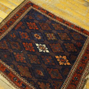 Navy blue and rust traditional rug with geometric medallions rests on distressed yellow plank flooring.