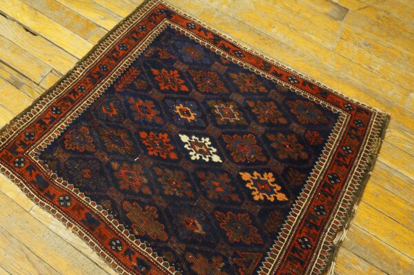 Navy blue and rust traditional rug with geometric medallions rests on distressed yellow plank flooring.