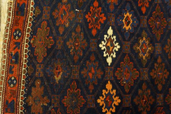 Geometric rug border and field with navy blue background and medallions in red, orange, and ivory.