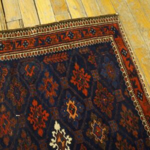 Textured navy rug with a repeating red and blue medallion pattern shown on distressed yellow hardwood.