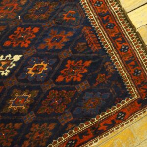 Navy blue rug featuring rust and cream geometric motifs and a red border on bright yellow wood flooring.