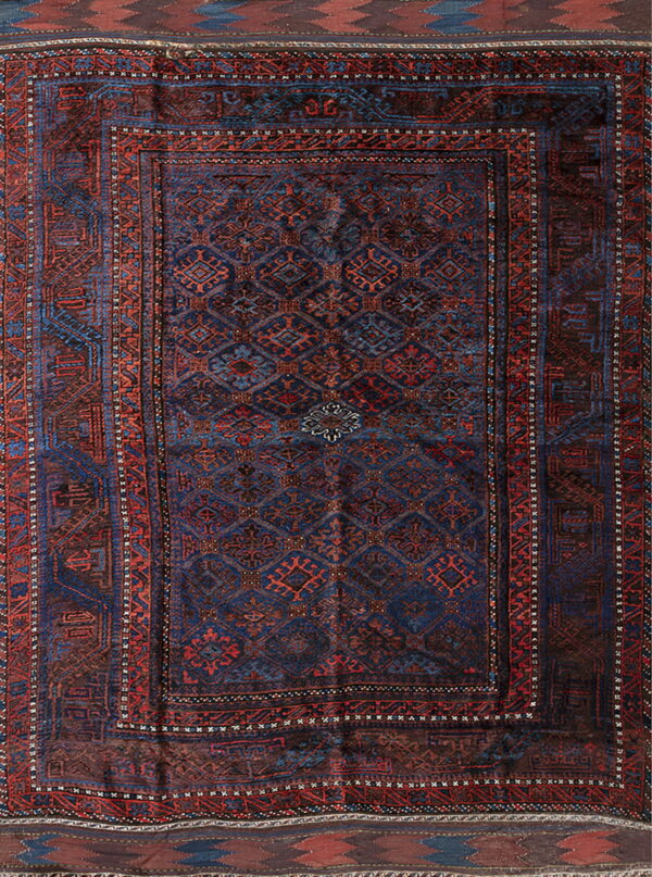 Traditional rug with a navy blue field, repeating geometric guls, and brick red and blue borders.