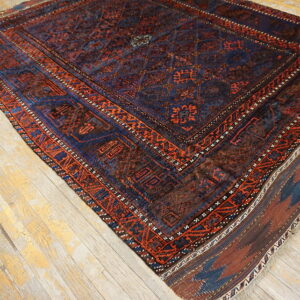 Traditional dark blue and rust geometric rug featuring medallions rests on distressed light wood floors.