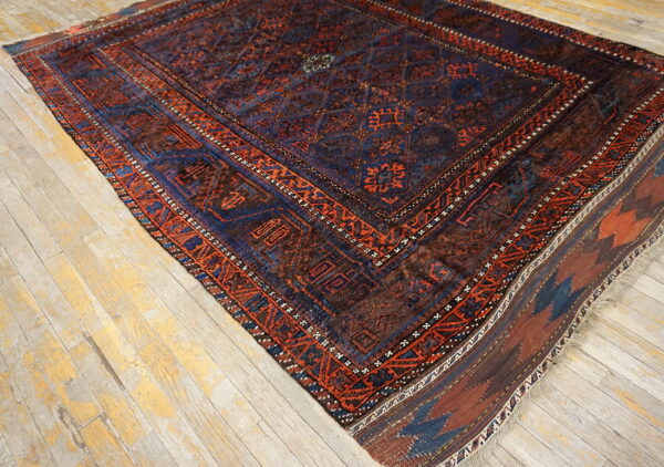 Traditional dark blue and rust geometric rug featuring medallions rests on distressed light wood floors.