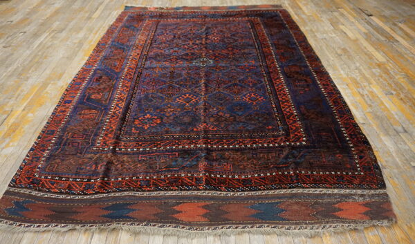 A dark blue and rust-red geometric patterned rug with low pile rests on distressed wooden floorboards.