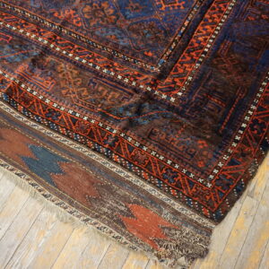 High-pile blue and rust geometric rug meets a flat-woven border on distressed light wood flooring.