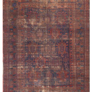 Heavily distressed low-pile rug with geometric patterns in deep red, blue, and brown tones.
