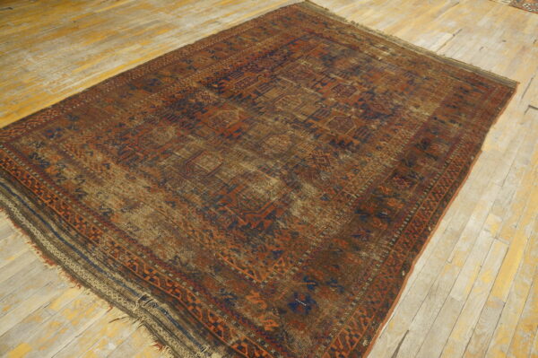 Distressed geometric rug featuring rust, navy, and brown patterns rests on light, visibly worn wooden floorboards.