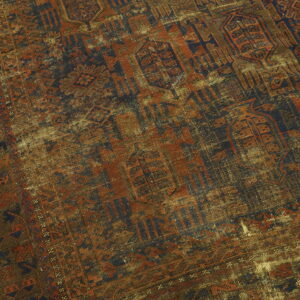 Heavily worn, low-pile rug displaying geometric patterns in distressed navy, rust, and tan.