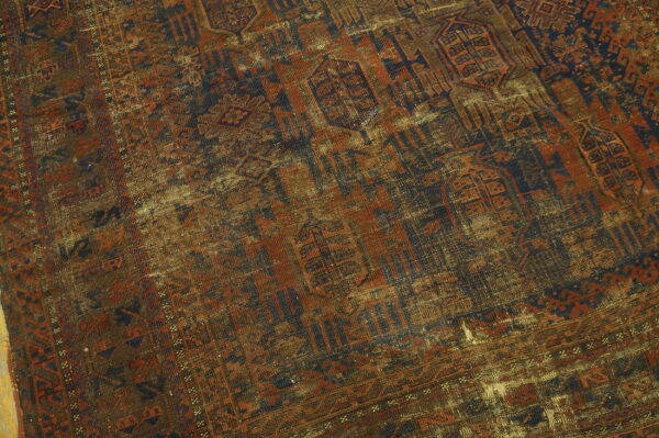 Heavily worn, low-pile rug displaying geometric patterns in distressed navy, rust, and tan.