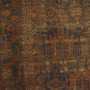 Geometric tribal rug detail in brown, rust, and dark blue, showing wear on light wood planks.