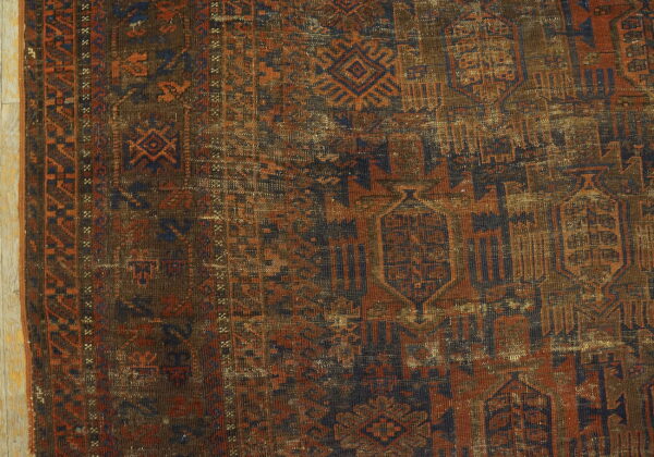 Geometric tribal rug detail in brown, rust, and dark blue, showing wear on light wood planks.