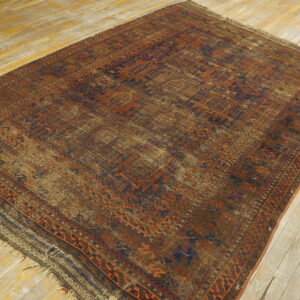 A worn low-pile rug with geometric patterns in rust, brown, and navy rests on light wood floors.