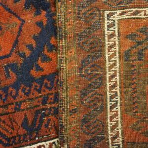 Detail shot of two adjacent rugs, showing dense pile red/blue pattern next to a flatweave brown border.