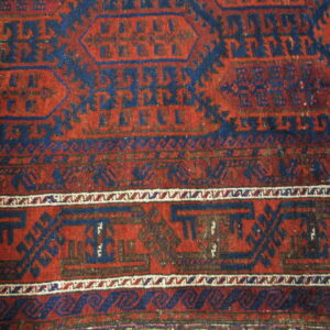 Red and navy geometric rug with detailed tribal motifs, striped borders, and a visibly low pile texture.