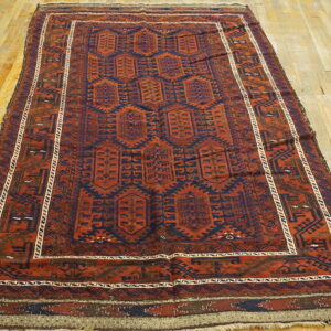 Rust and navy low-pile rug with repeating geometric medallions on light wood plank flooring.