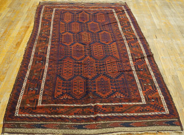 Rust and navy low-pile rug with repeating geometric medallions on light wood plank flooring.