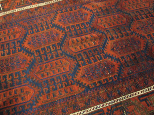 Close-up of a rug featuring rust red and navy blue geometric octagonal patterns and a white striped border.