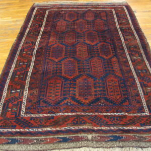 Low pile rug featuring red and dark blue geometric octagonal designs rests on a light wood floor.