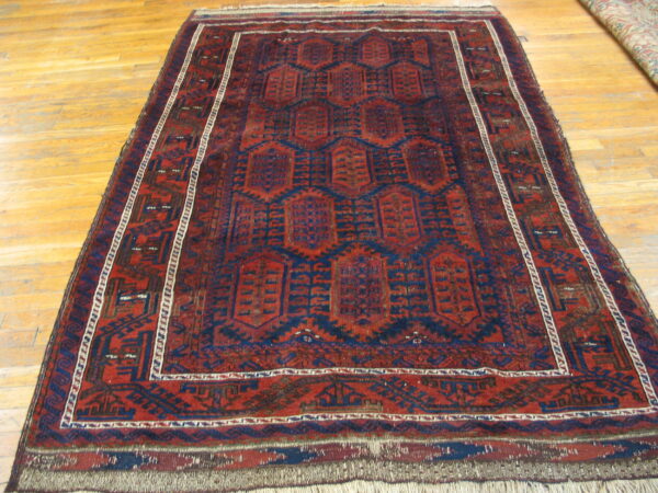 Low pile rug featuring red and dark blue geometric octagonal designs rests on a light wood floor.