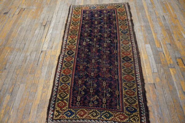 Navy and multicolor geometric runner rug displayed against distressed gray and yellow wooden planks.