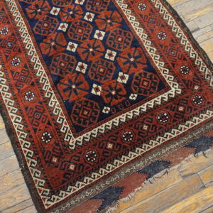 Low-pile geometric rug in navy and rust red with detailed borders on light wood flooring.