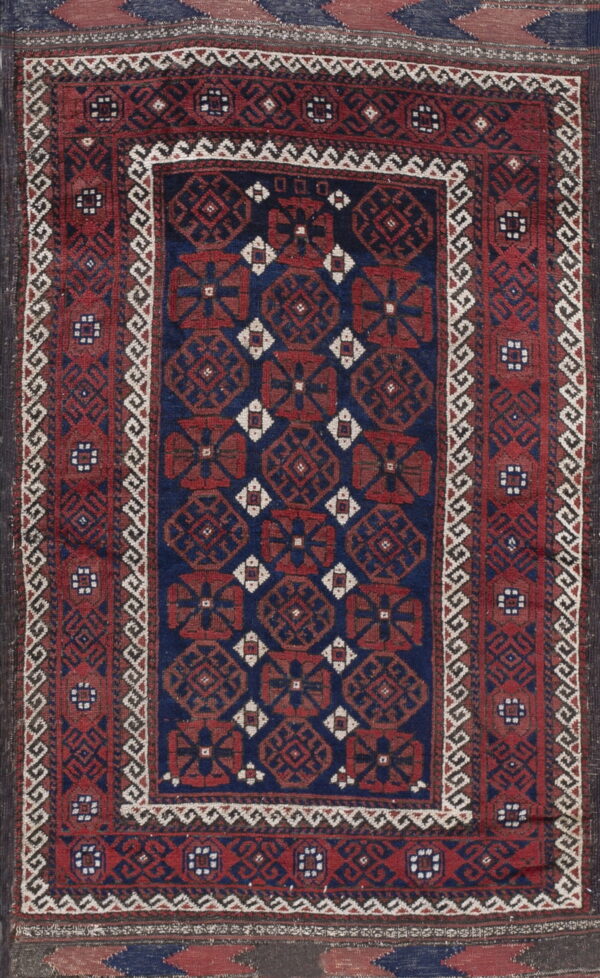Rectangular rug with a navy blue field and repeated red geometric octagons framed by elaborate red and white borders.