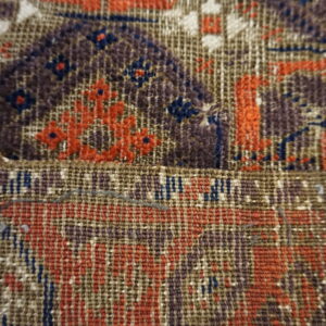 Detailed view of a rug showing dense pile and flat weave sections with orange, purple, and blue patterns.