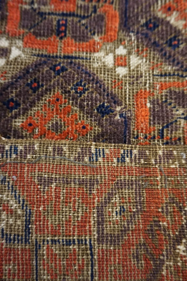 Detailed view of a rug showing dense pile and flat weave sections with orange, purple, and blue patterns.