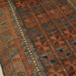 Geometric rug in deep brown, terracotta, and blue, featuring vertical stripes, shown on light plank flooring.