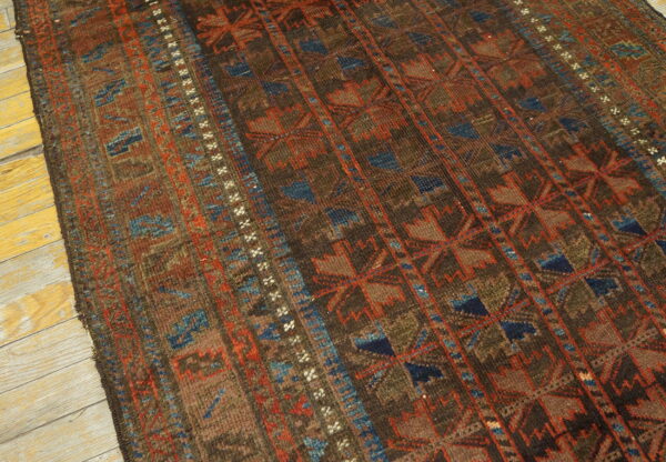Geometric rug in deep brown, terracotta, and blue, featuring vertical stripes, shown on light plank flooring.
