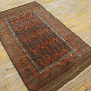 A brown and rust geometric tribal rug with blue accents rests on distressed yellow wood floors.