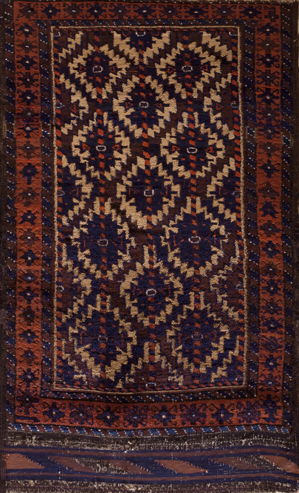 High-pile rug featuring a repeating geometric pattern in navy, tan, and dark brown with rust borders.