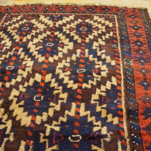 Geometric tribal rug featuring blue, red, and tan patterns on light wooden floorboards.
