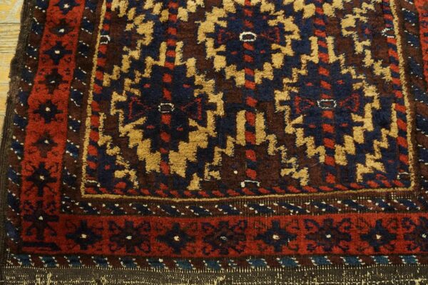 Thick pile rug detail featuring traditional geometric patterns in navy, rust, tan, and brown over wood.