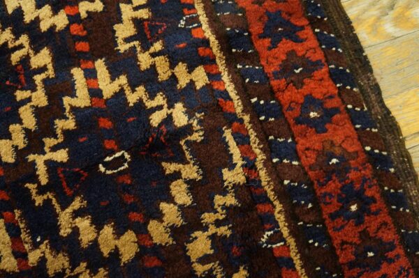 High-pile rug with geometric gold, navy, red, and brown patterns rests on light wood planks.