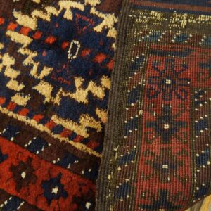 Close-up of a rug revealing the navy, red, and tan geometric pile and the tightly woven reverse side.