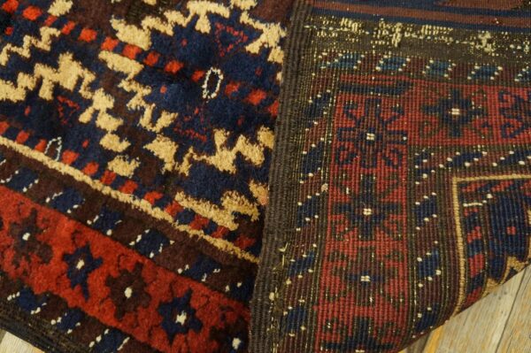 Close-up of a rug revealing the navy, red, and tan geometric pile and the tightly woven reverse side.