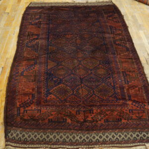 Long traditional rug featuring geometric patterns in deep red and dark blue on a light wood floor.