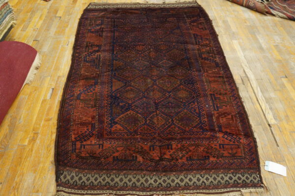 Long traditional rug featuring geometric patterns in deep red and dark blue on a light wood floor.