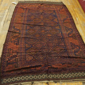 Traditional reddish-brown and dark blue geometric rug with diamond designs lying on a wood floor.