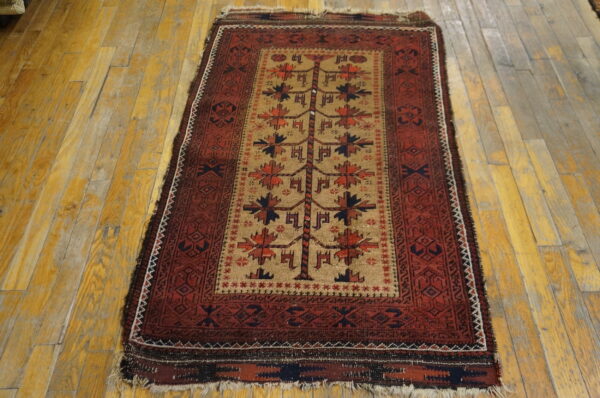 Geometric red and tan rug with a central tree motif displayed on distressed hardwood planks.