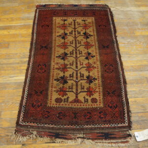 Small maroon and tan rug with a central stylized tree and animal pattern on wood planks.