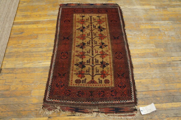 Small maroon and tan rug with a central stylized tree and animal pattern on wood planks.
