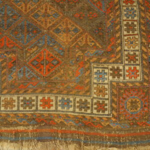 Geometric rug displaying brown, rust, blue, and cream motifs next to yellow distressed wood planking.