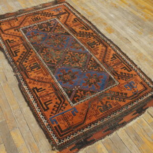 Low-pile orange and blue geometric rug with dark borders on distressed plank flooring.