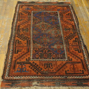 Geometric rug featuring rust orange, black, and blue patterns rests on distressed wooden floorboards.