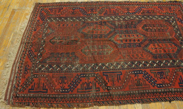 A deep red geometric rug featuring dark blue medallions rests on plank hardwood flooring.