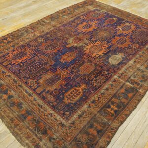 Heavily worn, low-pile rug with geometric blue and orange patterns displayed on yellow wood flooring.