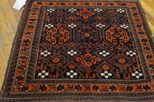 Low-pile rug with geometric and animal motifs in navy, rust, and brown, placed on a wood floor.